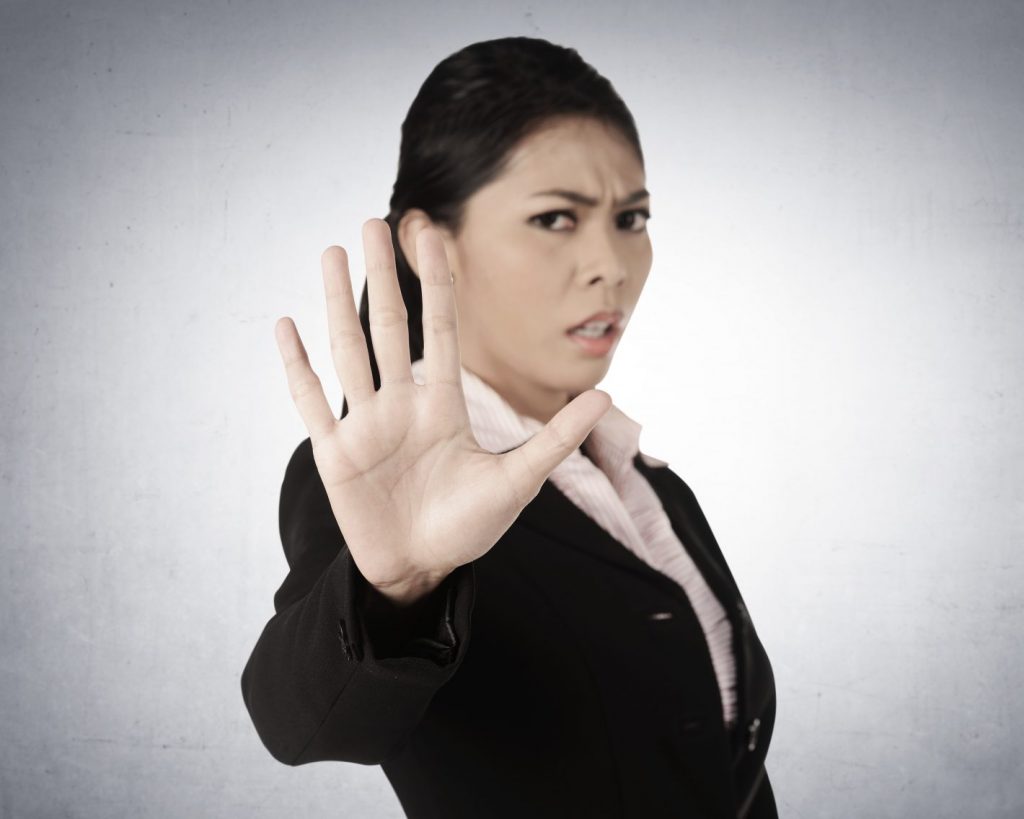 Business woman says no with hand out in your face, with grunge wall background