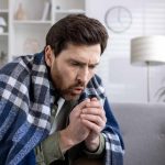 Man feeling cold and ill sitting on couch heater not working